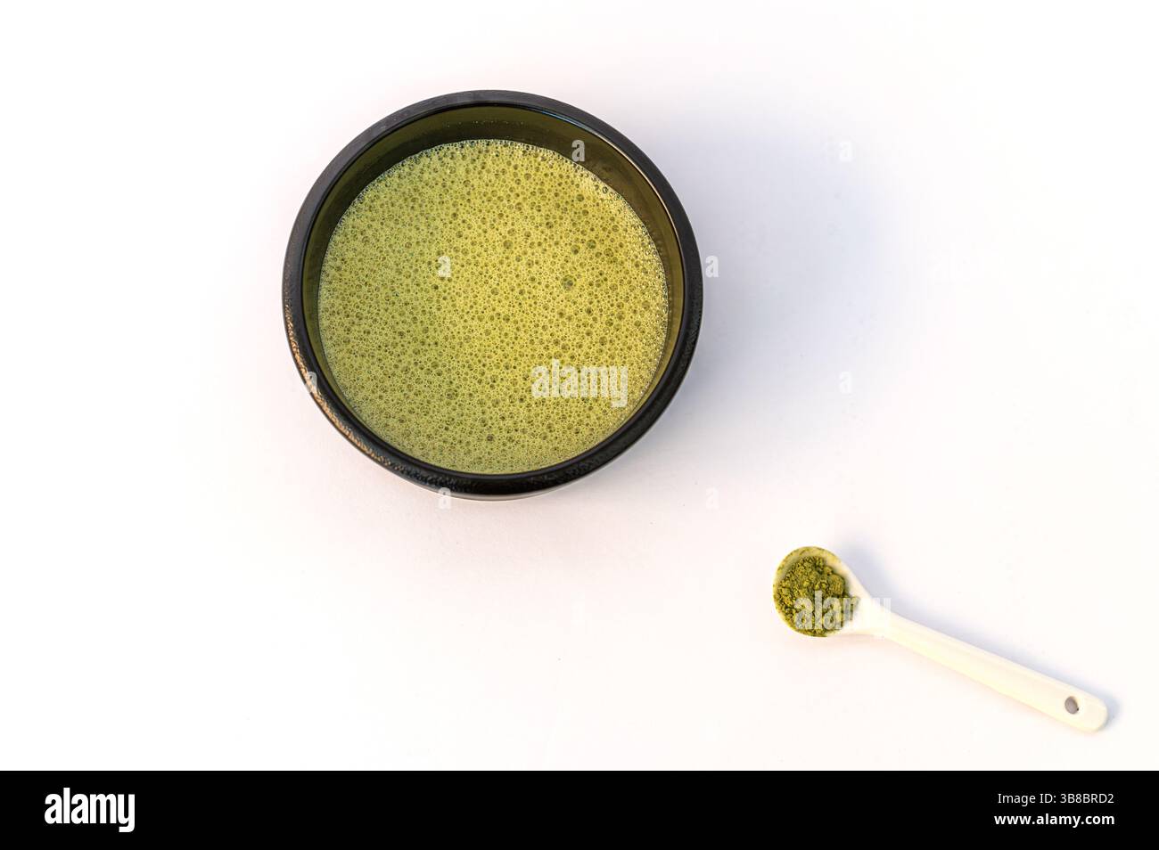 A vibrant green matcha drink alongside a bowl of fine matcha powder, presented on a clean white background for a fresh and minimalistic look. Stock Photo