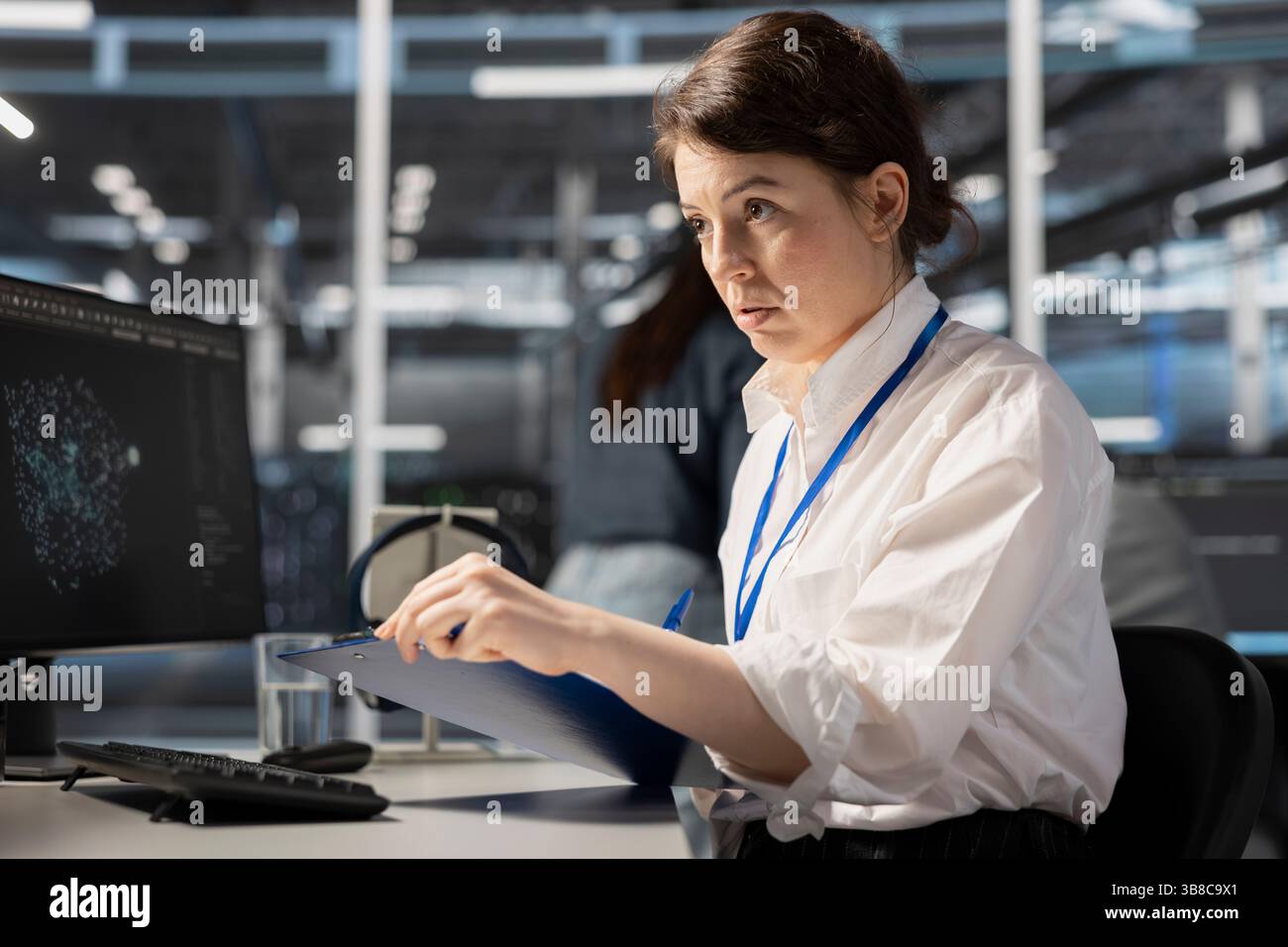 Data center admin monitoring system performance using PC, looking over maintenance paperwork. Server farm worker reading documentation files to implement optimizations Stock Photo