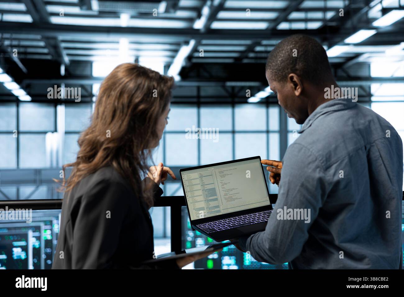 Programmers using laptop in data center, managing server virtualization, running scripts. IT experts using programming language on notebook in server hub, finetuning network protocols Stock Photo