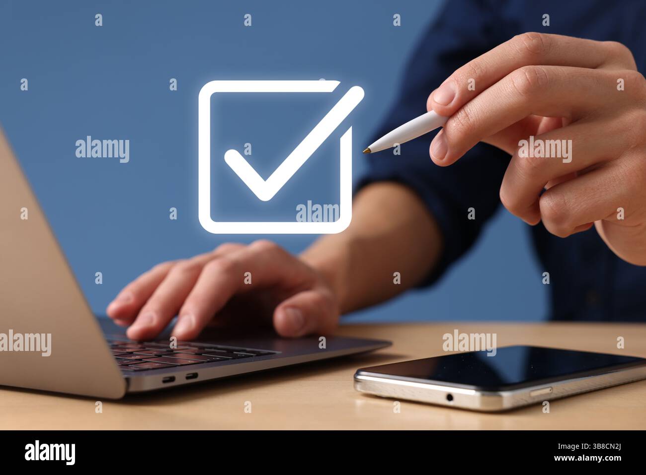 Approved. Man using laptop and touching virtual screen with check mark at table, closeup Stock Photo