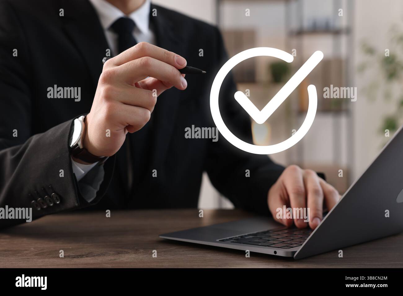 Approved. Man using laptop and touching virtual screen with check mark at table, closeup Stock Photo