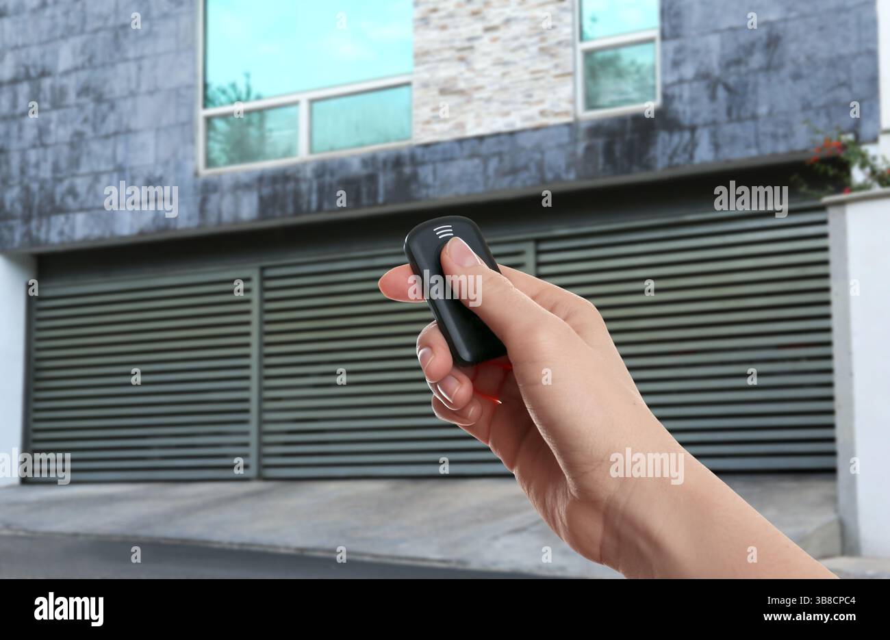 Woman using remote to control roller shutters outdoors, closeup Stock Photo