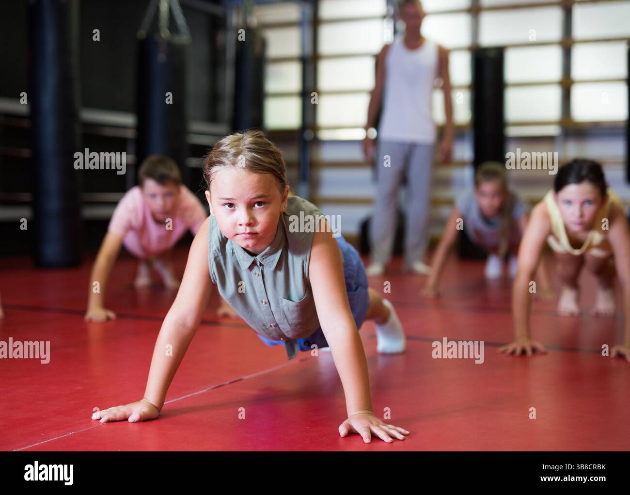 Children doing bench press exercises in gym Stock Photo