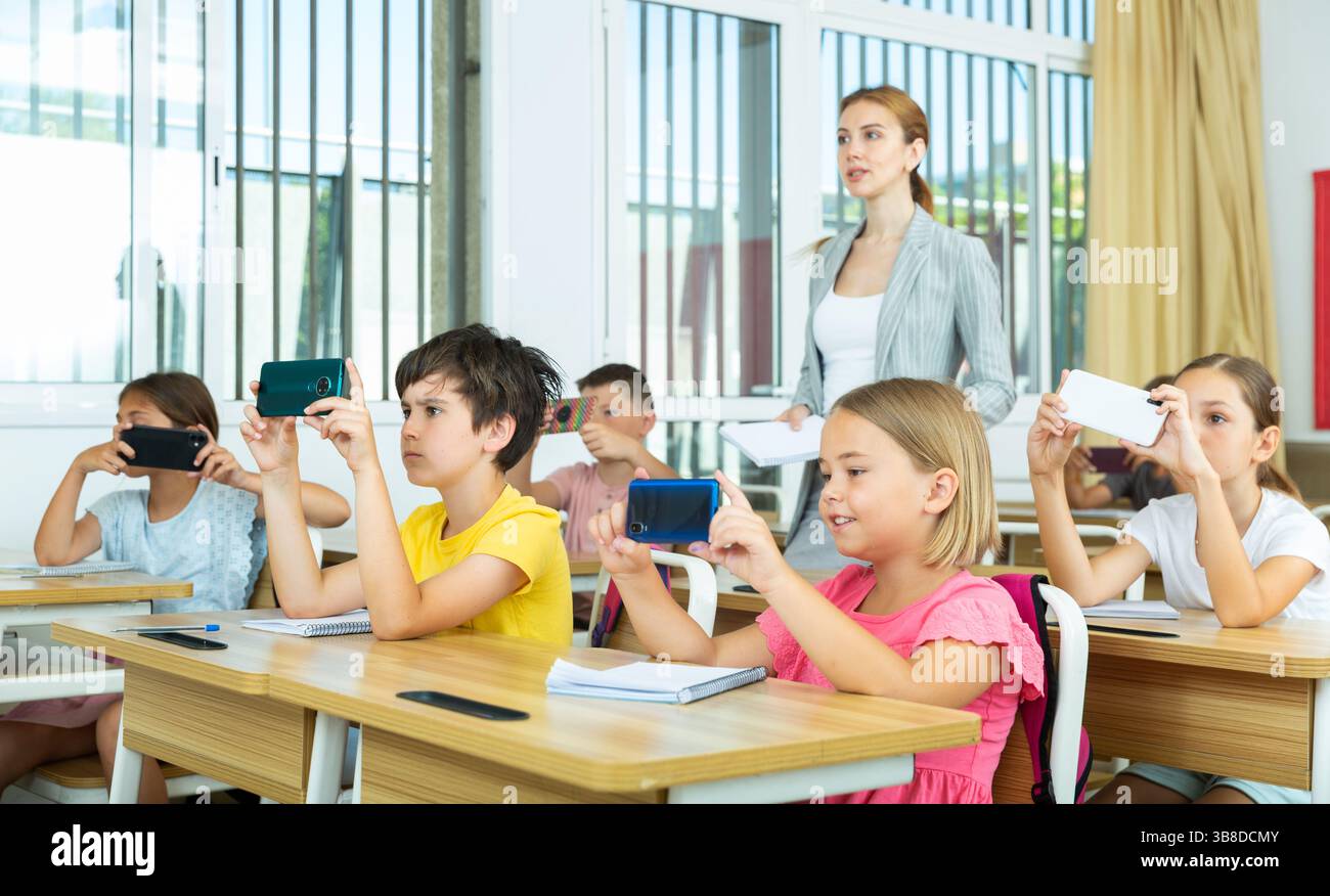 Pupils using mobile phones during lesson in school Stock Photo
