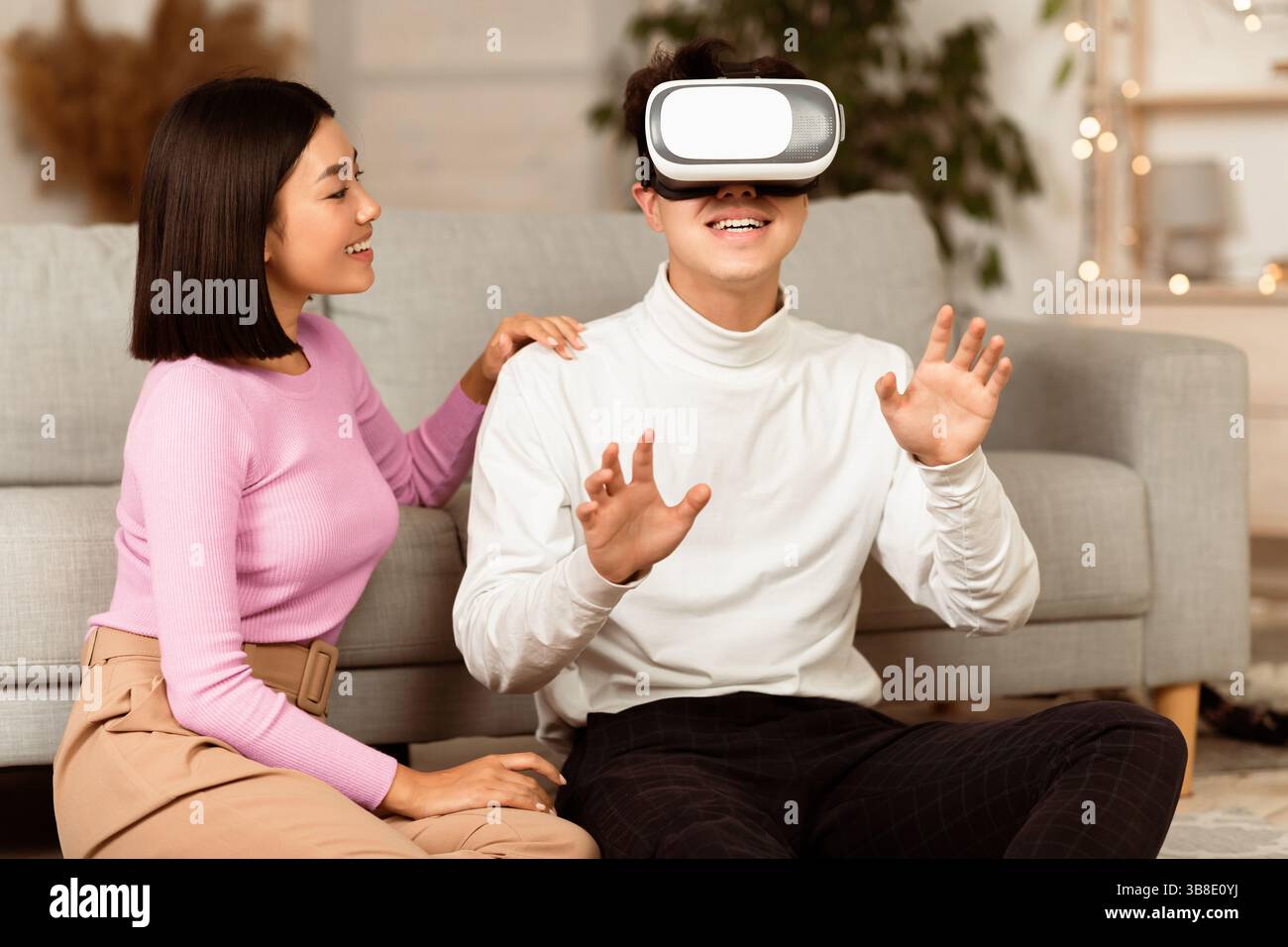 Asian Couple Using Virtual Reality Headset Having Fun At Home Stock Photo