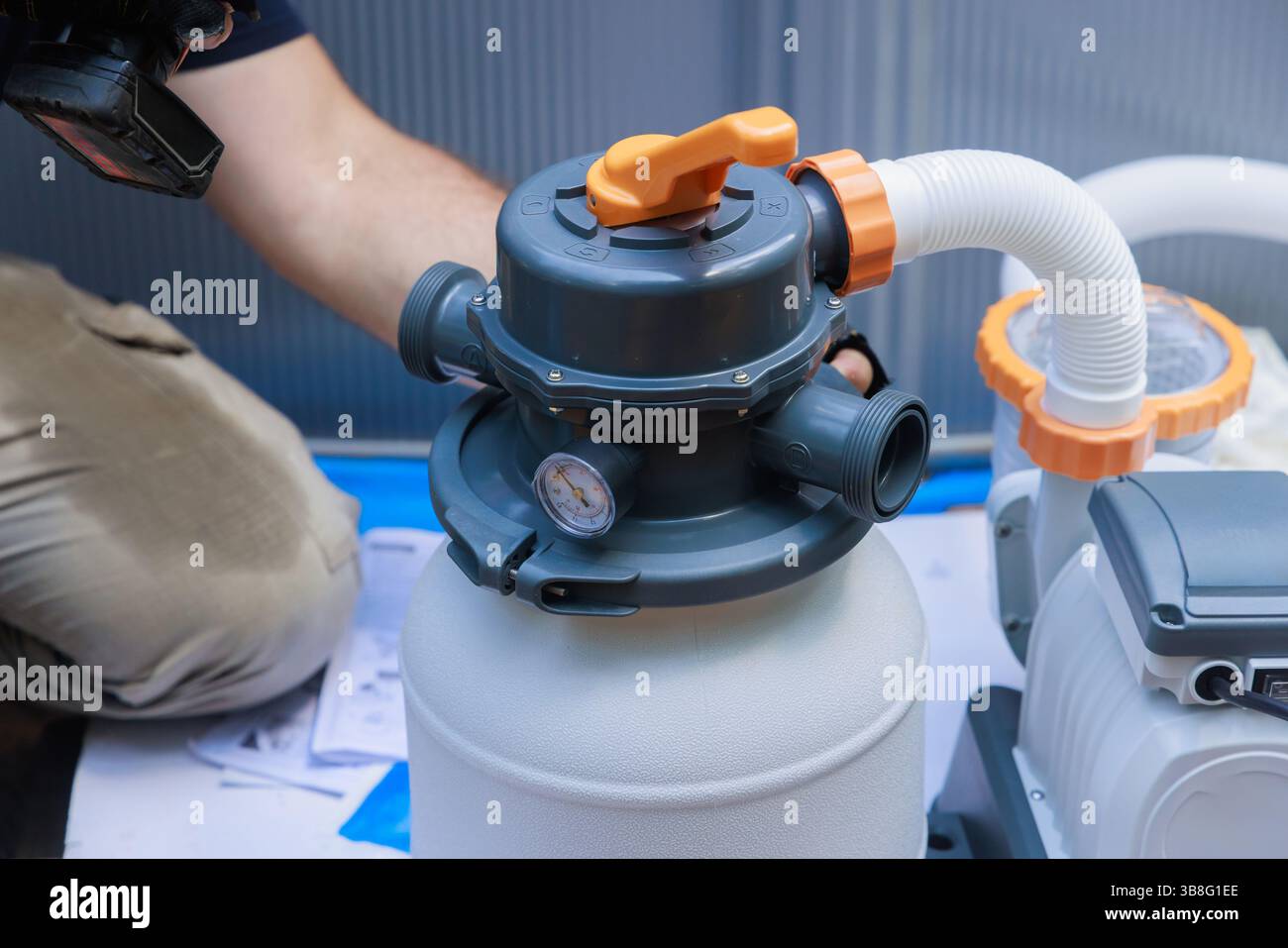 Plumber is installing pool filter system, checking connections gauges in backyard environment. Stock Photo