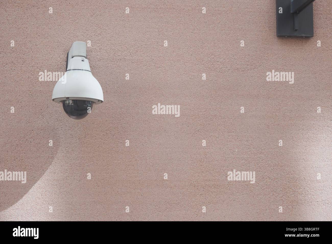Security camera mounted on a beige wall for monitoring purposes Stock ...