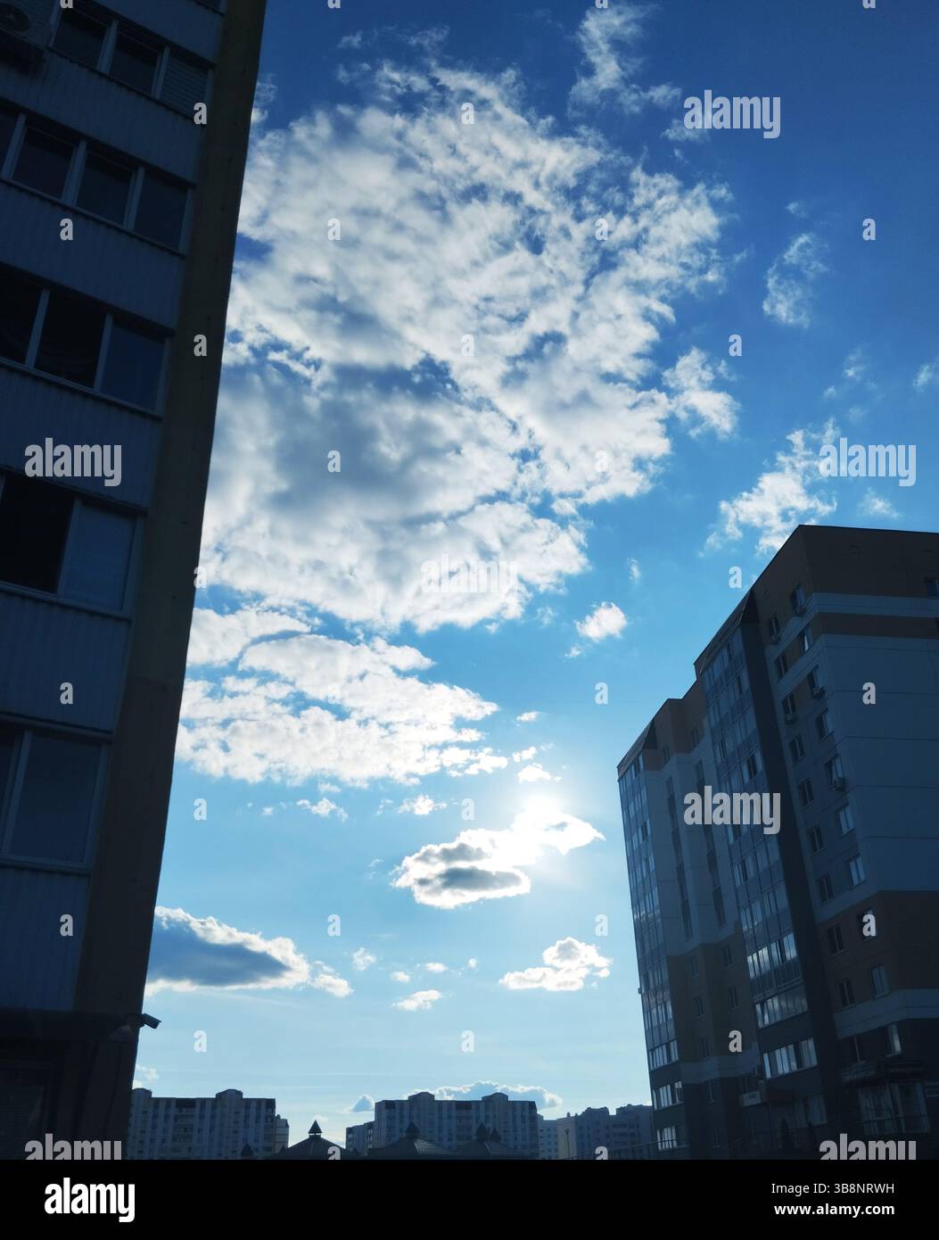 Blue sky with white clouds on a sunny day between houses. Cityscape. Stock Photo