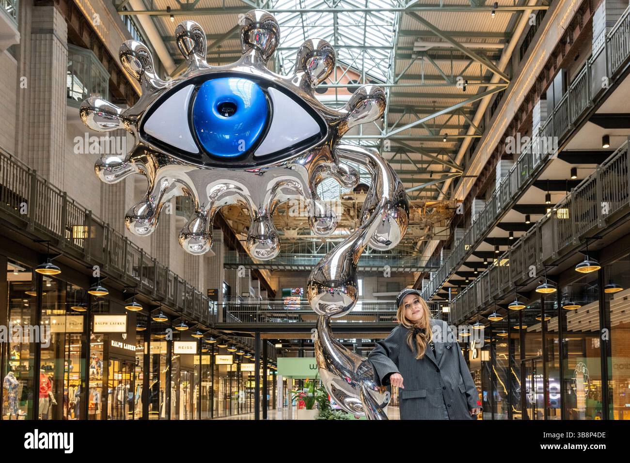 London, UK.  8 May 2025.  Unveiling of ‘Dreamland Sirens’, a dual-coloured eye sculpture supported by a column of tears, displayed in Battersea Power Station, by multimedia artist Charlotte Colbert (pictured).  The sculpture draws inspiration from Lewis Carroll's Alice in Wonderland and is part of the artist’s Chasing Rainbow series on show in the Turbine Hall until 1 June for London Craft Week.  Credit: Stephen Chung / Alamy Live News Stock Photo