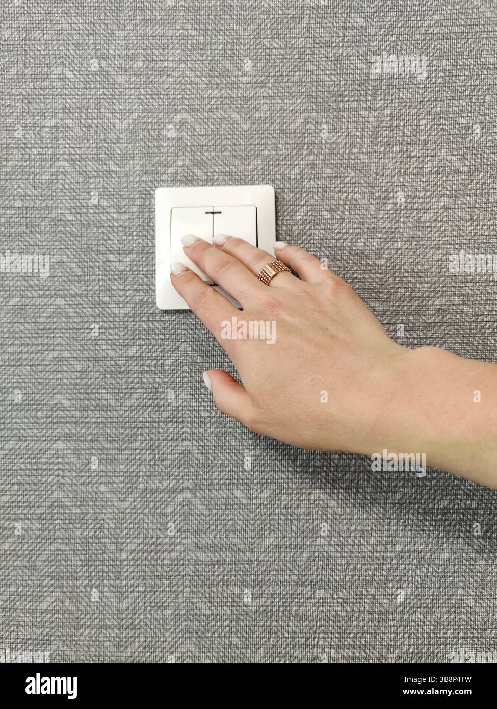 Turning light on / off. Woman pressing light switch on patterned wall ...