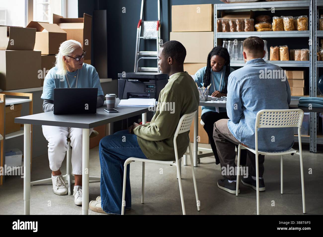 Diverse Team Having Meeting in Modern Warehouse Setting Stock Photo
