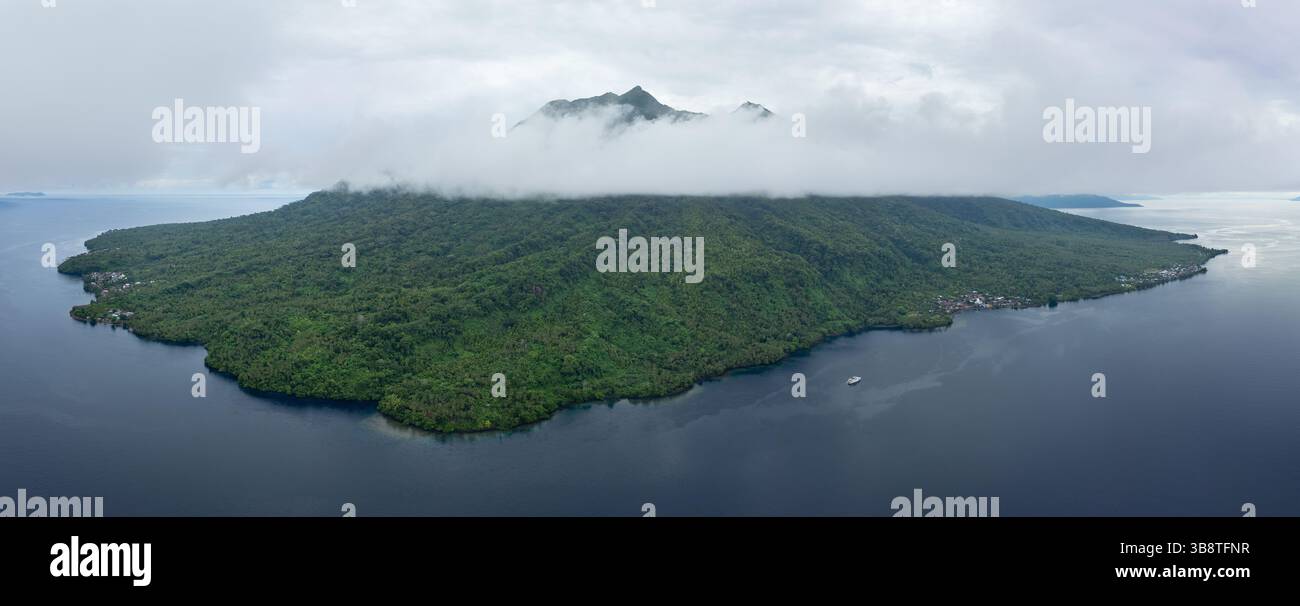 Low clouds cover the rainforest-covered, volcanic island of Damar, near ...