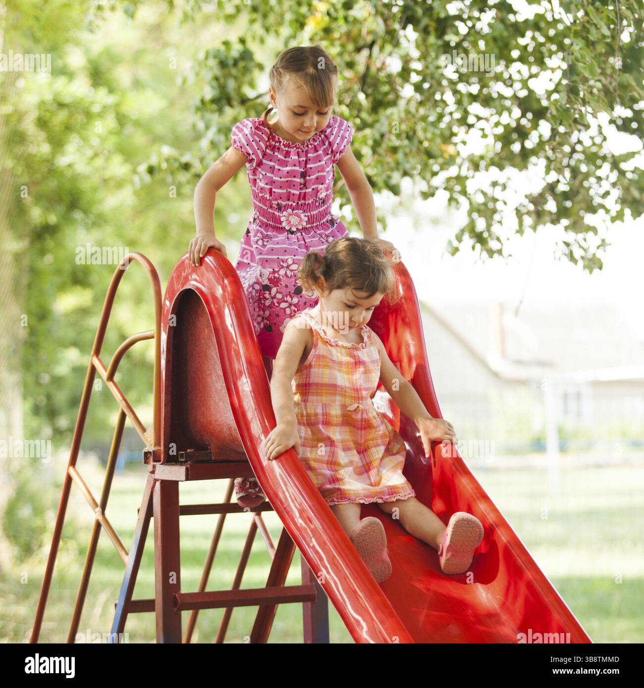 Two preschool girls on the slide at the playground Stock Photo - Alamy
