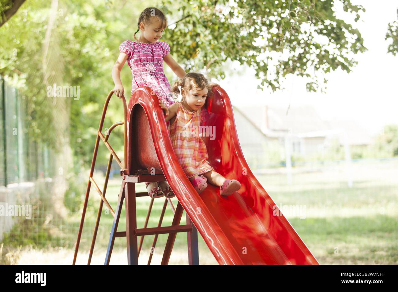 Two preschool girls on the slide at the playground Stock Photo - Alamy