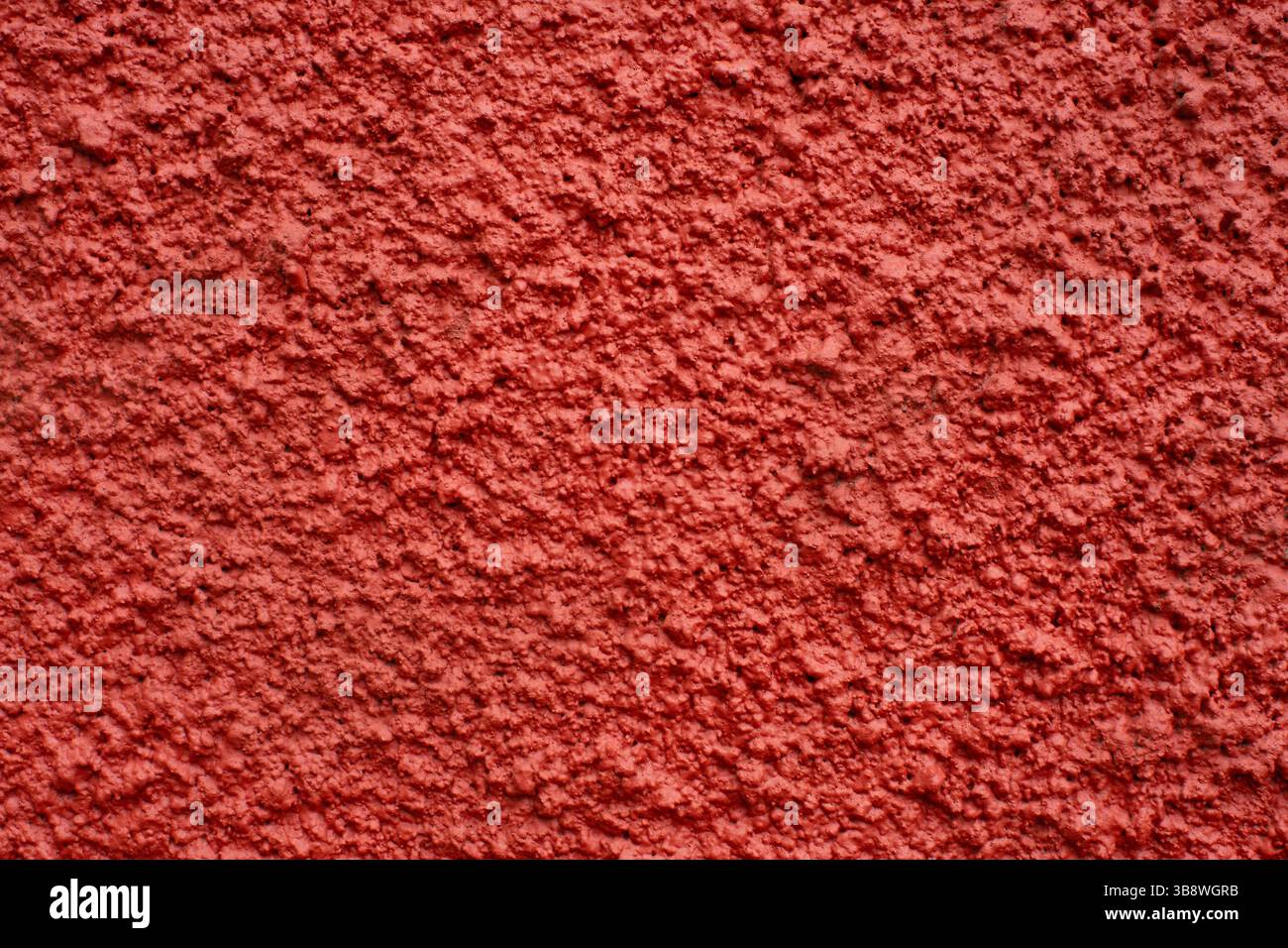 Red rough wall texture. Stucco plaster background. Painted surface closeup with grunge detail. Solid building material with abstract structure. Stock Photo