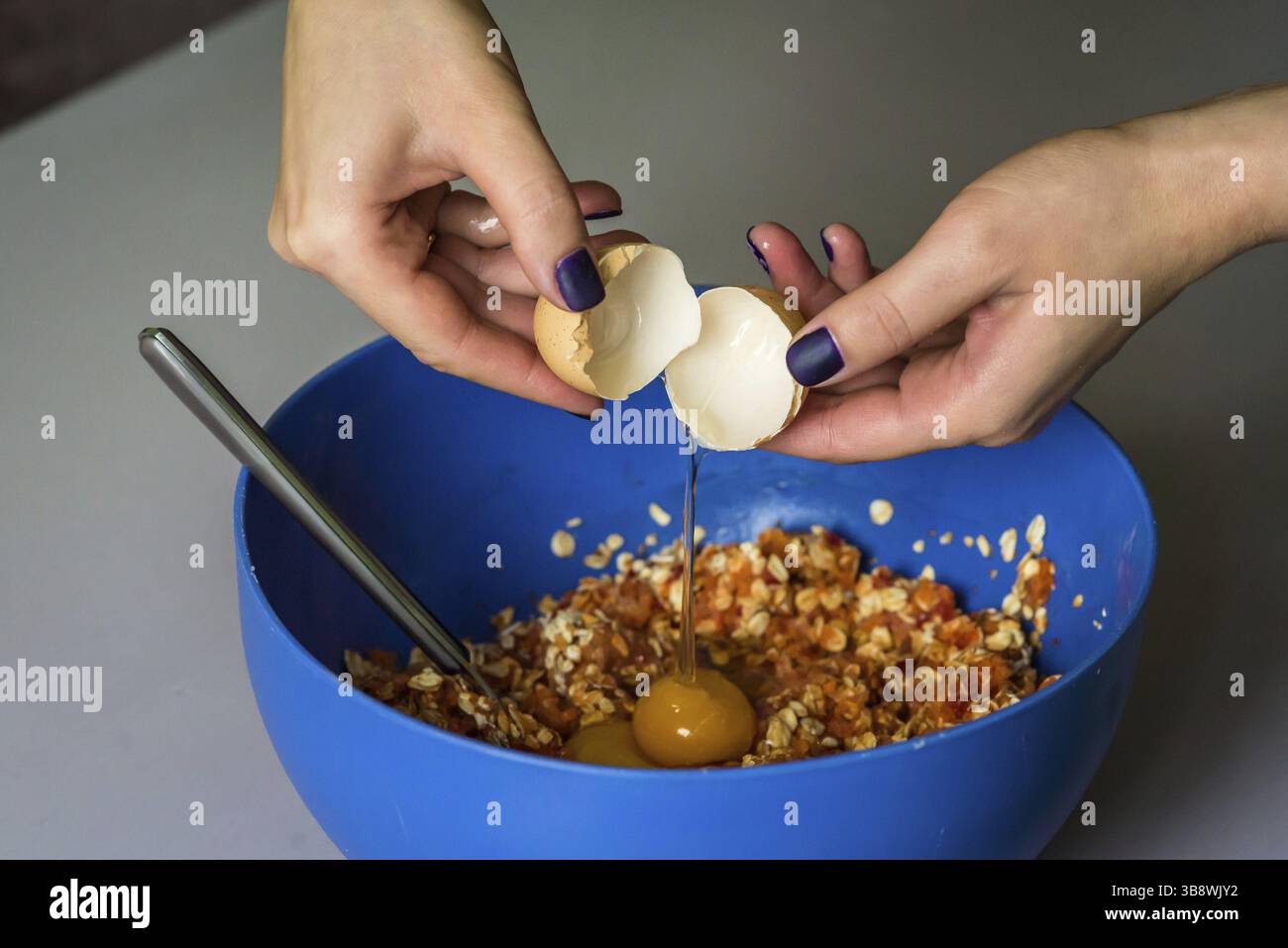 Hand poured down a raw egg with shell in blue bowl Stock Photo