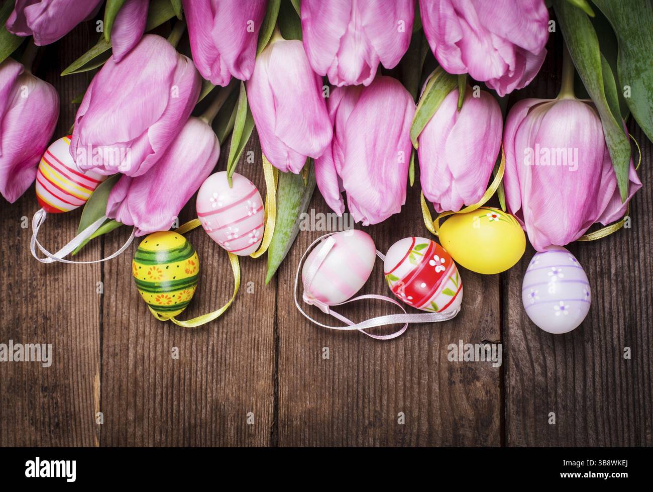 Tulips and eggs border over wooden backdrop. Easter decorations Stock Photo
