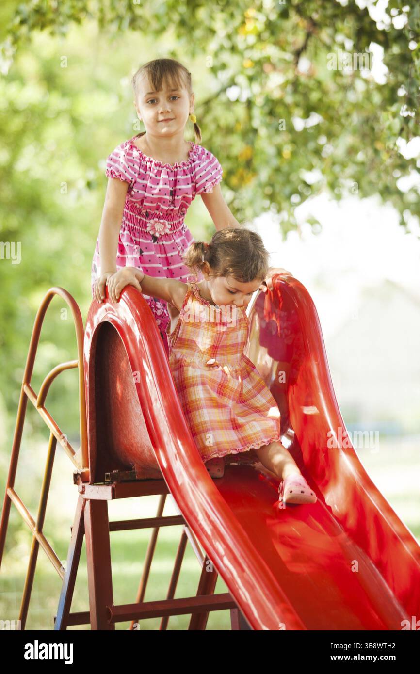Two preschool girls on the slide at the playground Stock Photo - Alamy