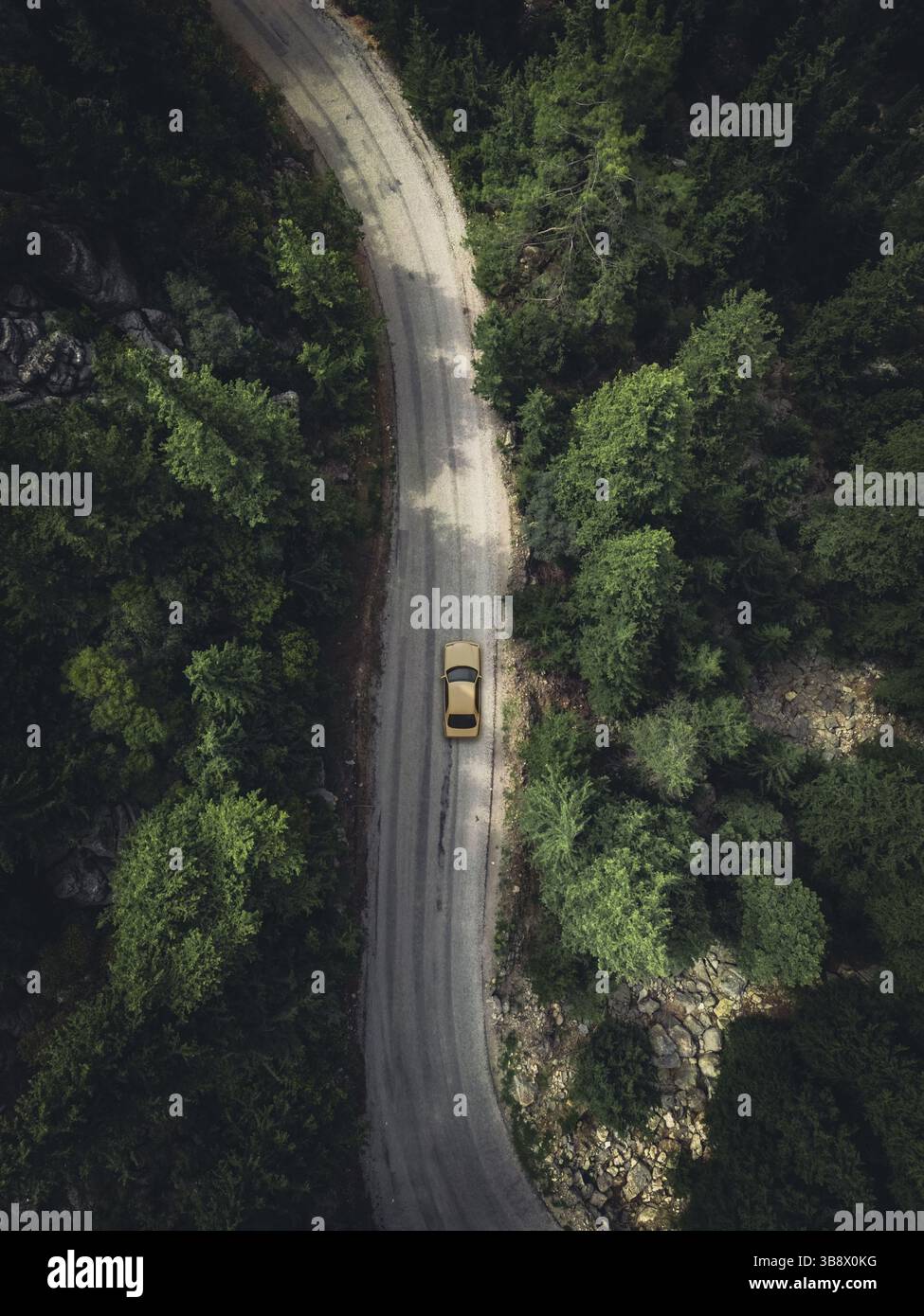 Aerial view taken by drone of a car driving on a forest road in autumn ...