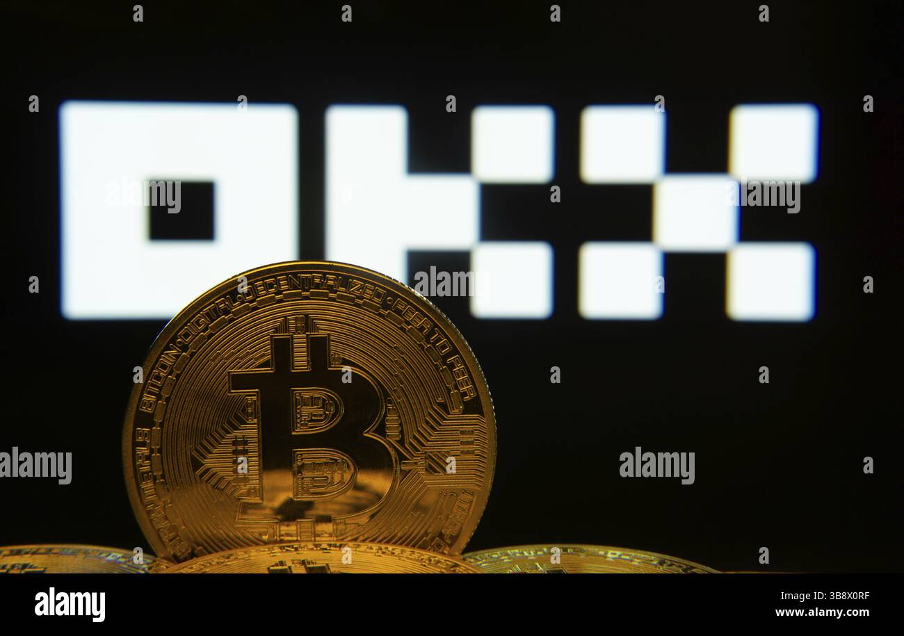 Dhaka, Bangladesh- 04 April 2025: Close-up of Bitcoin coins with the OKX logo visible on a screen in the background Stock Photo