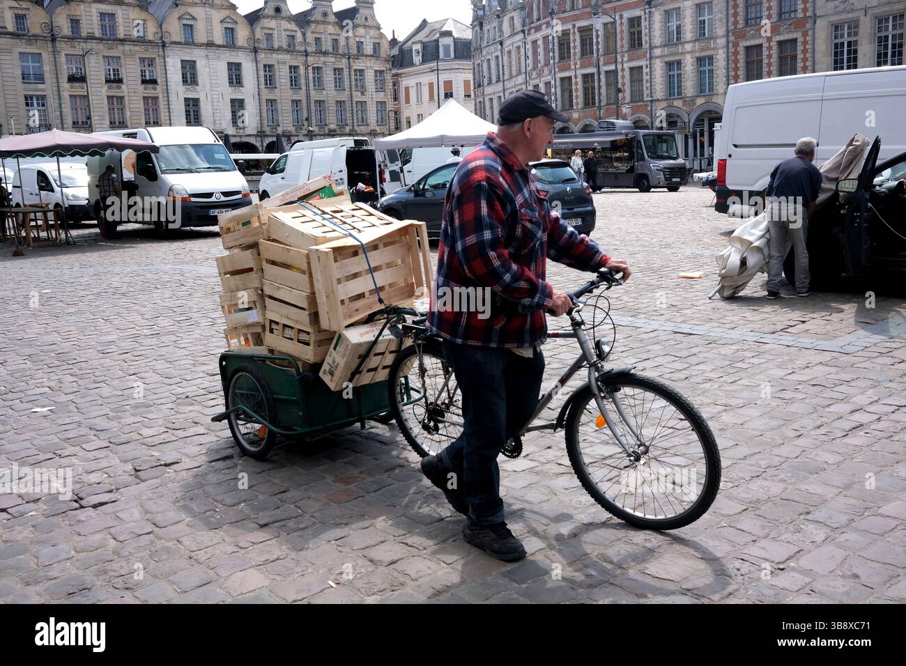 The Place des Héros in Arras in Pas-de-Calais, Northern France. outdoor market stall holders closing as man helps collect wooden pallets Stock Photo