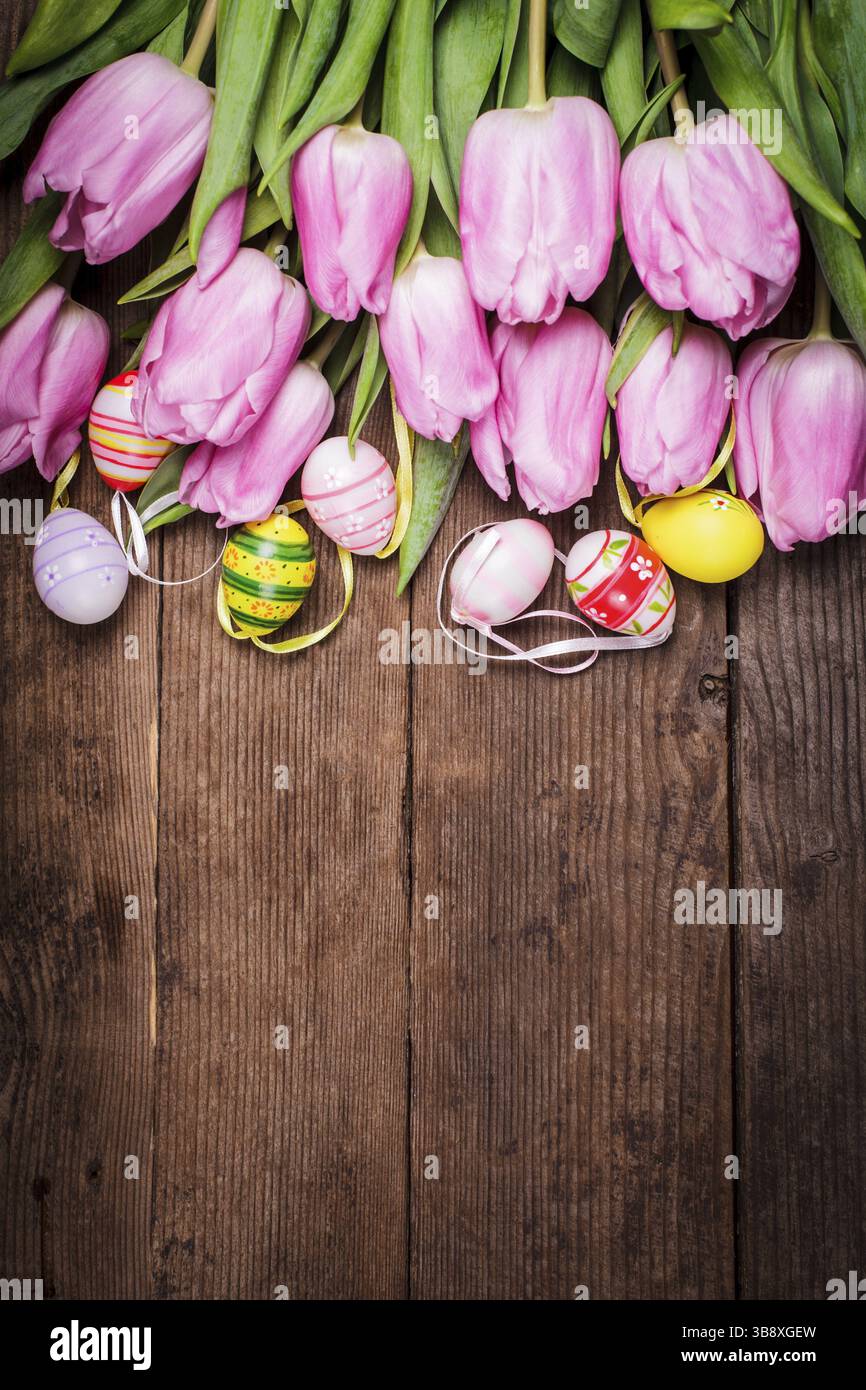 Tulips and eggs border over wooden backdrop. Easter decorations Stock Photo