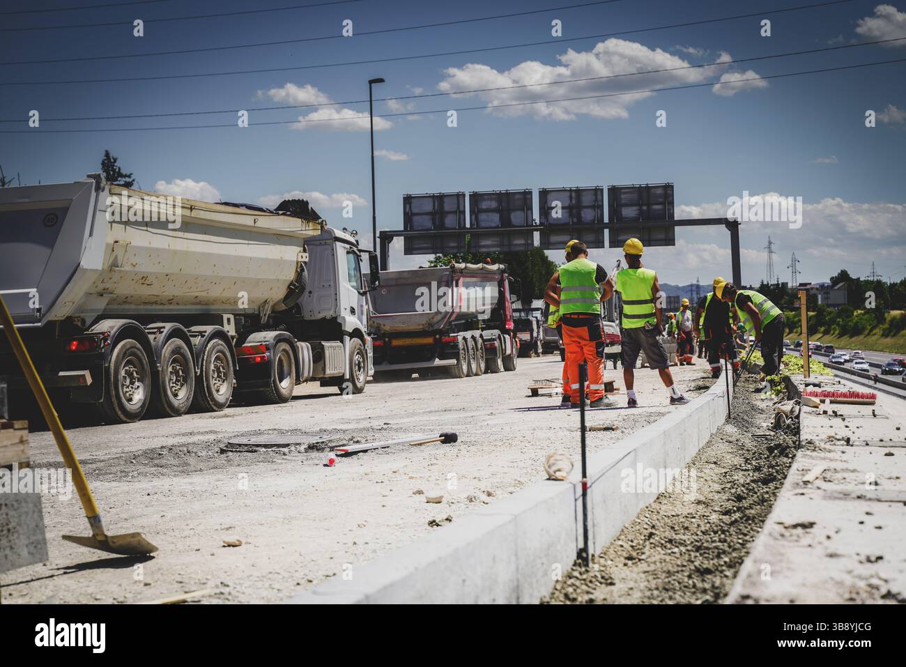 Construction workers placing concrete road curbs at highway ramp Stock ...