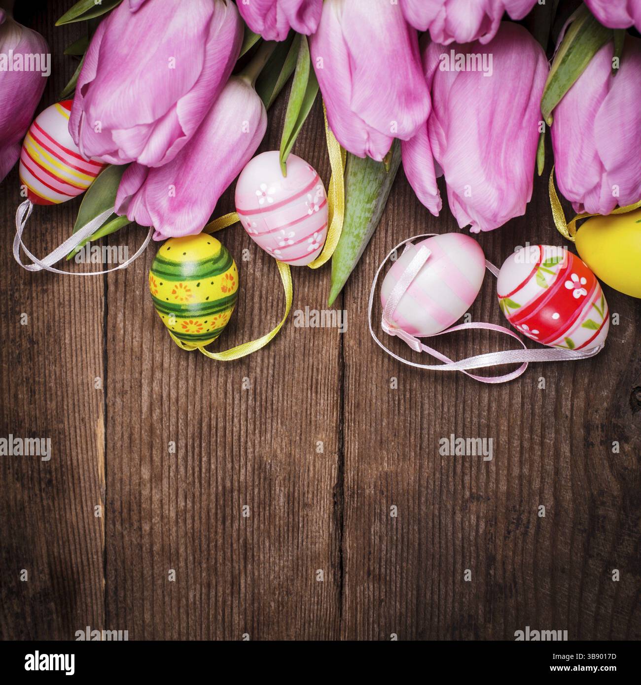 Tulips and eggs border over wooden backdrop. Easter decorations Stock Photo