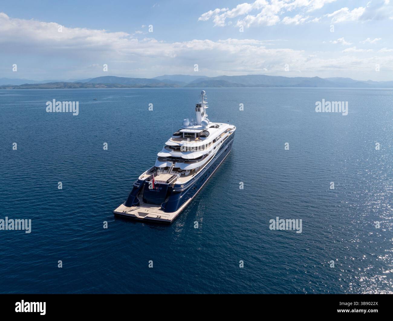 Aerial view of a luxurious yacht at sea, mountains in the background ...
