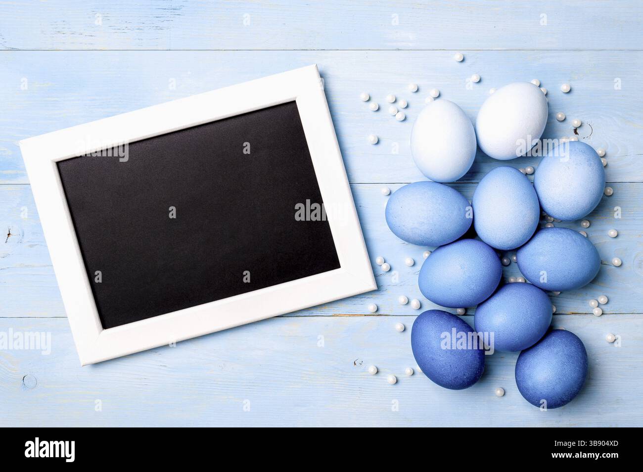 Easter concept. Ombre eggs in blue colors on blue wooden background with empty chalkboard. Top down view or flat lay. Classic blue colors in Easter 20 Stock Photo