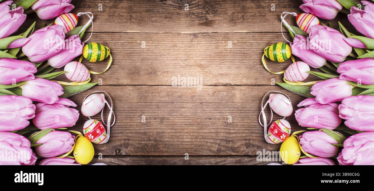 Tulips and eggs border over wooden backdrop. Easter decorations Stock Photo