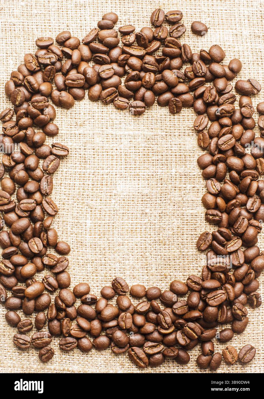 Spilled coffee beans frame over burlap textile Stock Photo