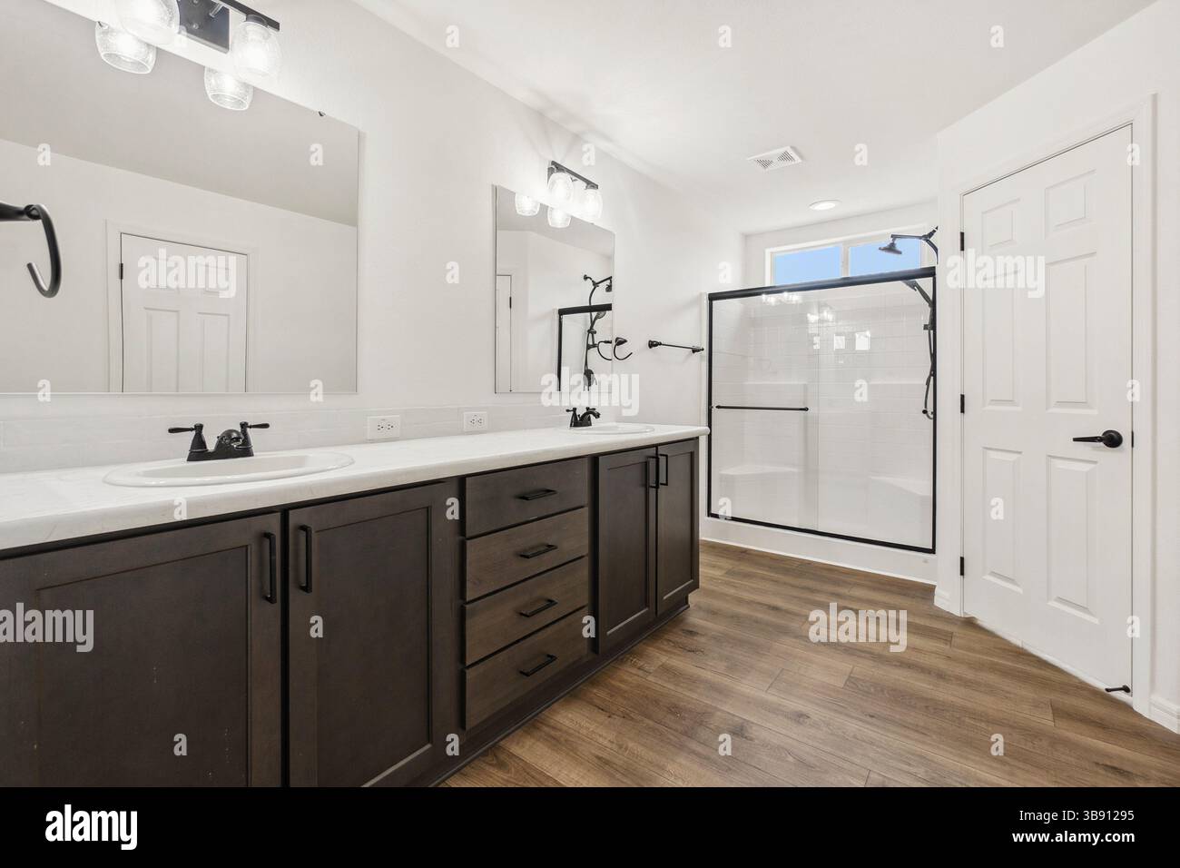 A bathroom with two sinks, mirrors, and a walkin shower Stock Photo