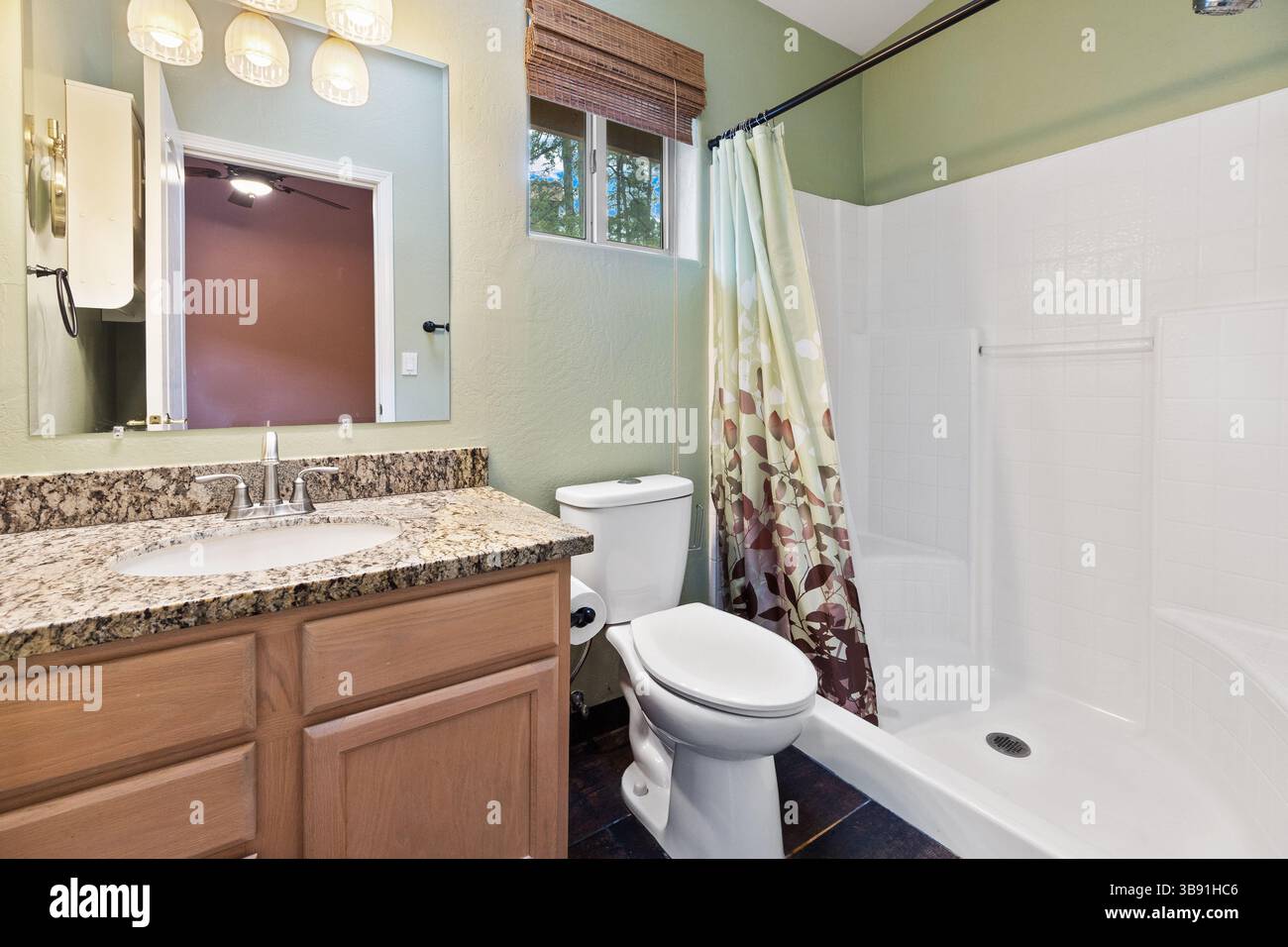 A spacious bathroom featuring a toilet, sink, shower, and mirror Stock Photo