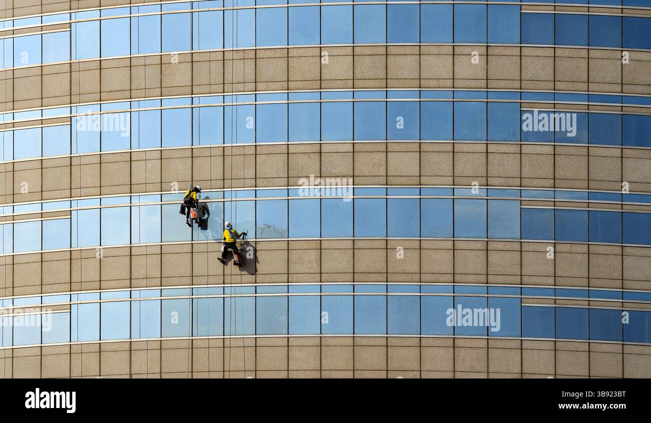high rise building Window washers cleaning the glass facade of a modern ...