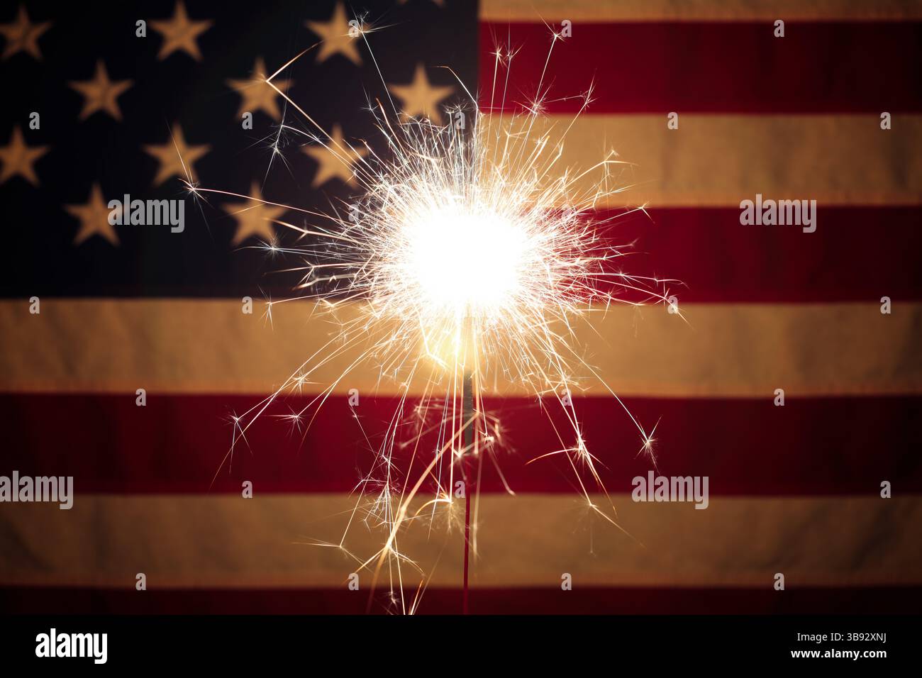 Lit sparkler in front the American Flag for 4th of July celebration ...