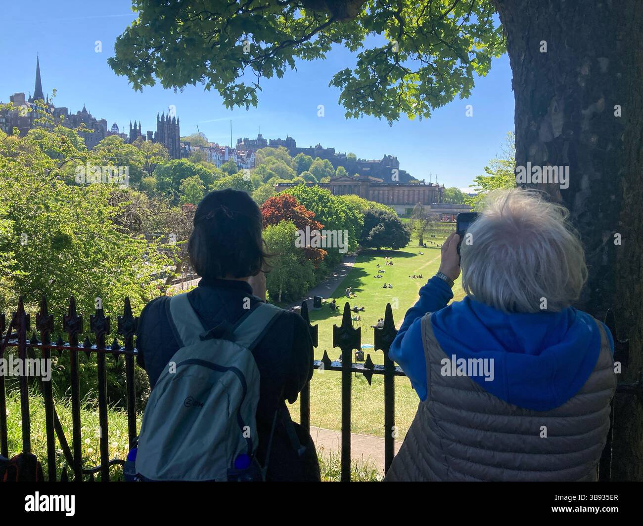 Visitors taking a photo of Edinburgh Castle from Waverley bridge over Princes Street gardens, Edinburgh Scotland - Smartphone Captured Stock Image