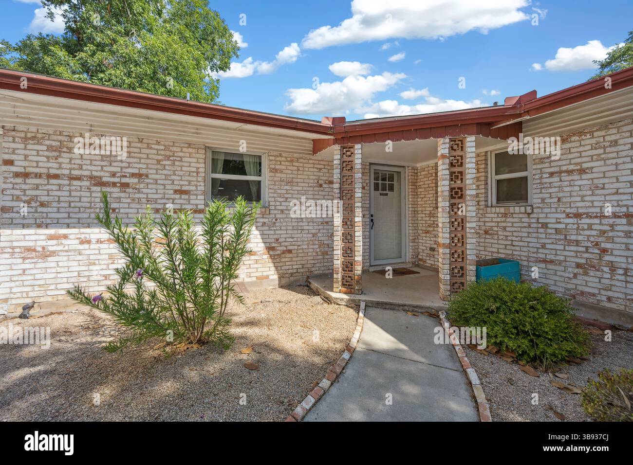 A charming white brick house featuring a lovely porch and a wellkept ...