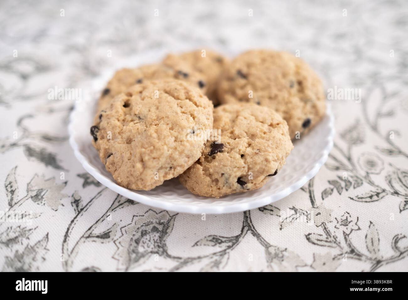 Small wicker white plate with five delicious chocolate chips gluten free cookies. They are fresh, baked and handmade. The dish is placed on a classic Stock Photo