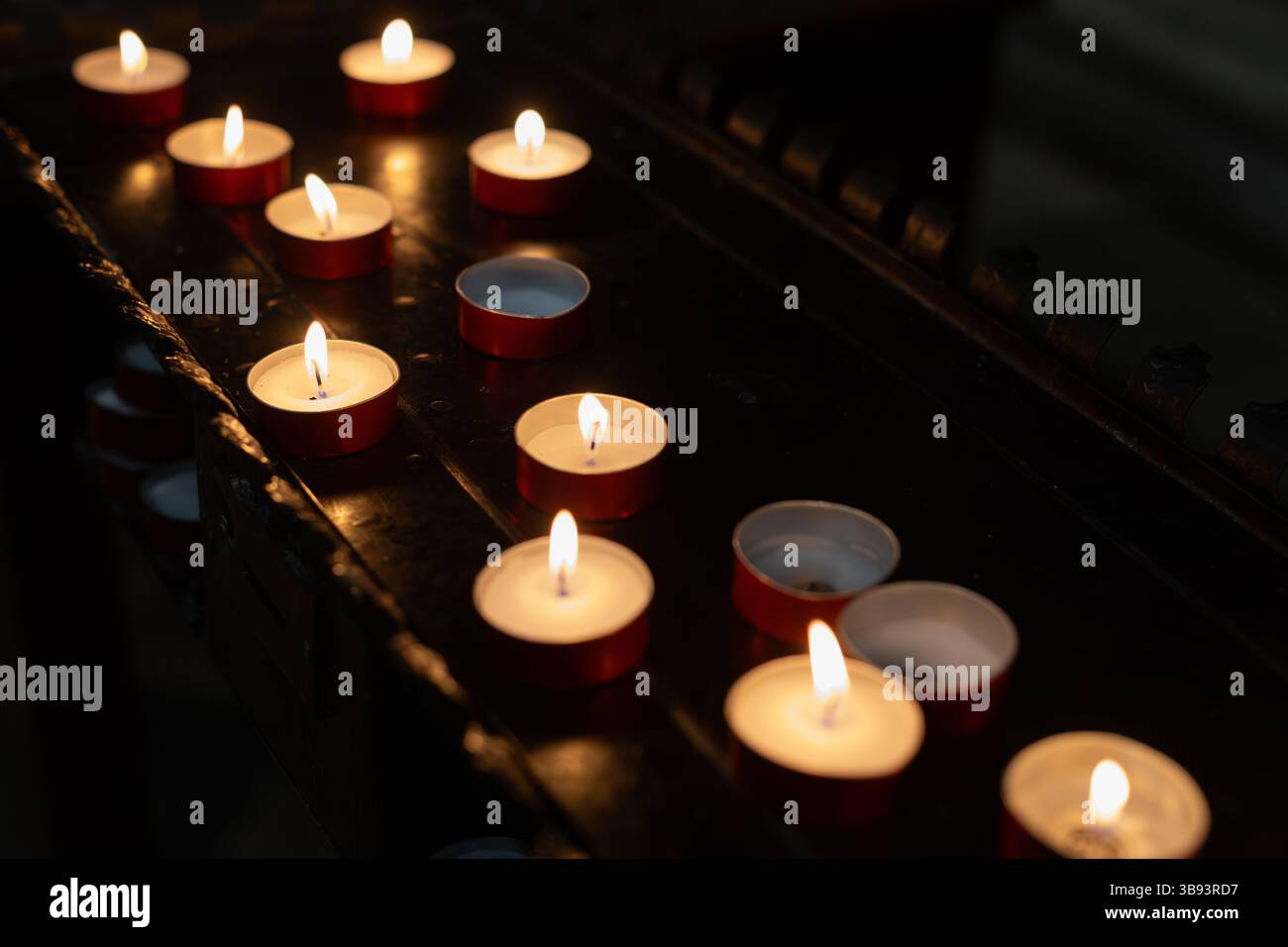 Multiple Tealight Candles Burning in Darkness Stock Photo