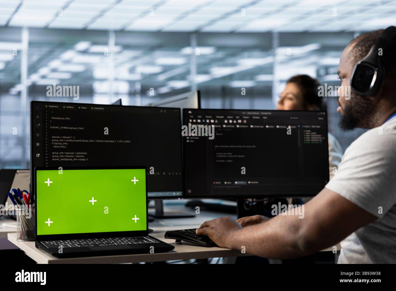 Isolated screen laptop next to man coding in server farm while listening music in headphones. Worker safeguarding hardware against unauthorized access with chroma key notebook, hearing songs Stock Photo
