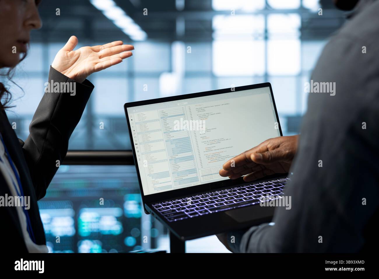 Software developers using laptop in data center, managing server virtualization. IT expert coding on notebook in server room, finetuning network protocols, enforcing advanced security measures Stock Photo