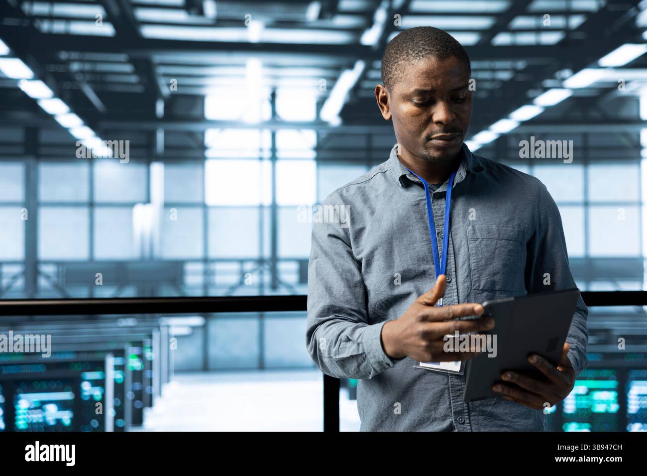 Computer scientist in data center uses tablet, verifying compliance of racks. IT expert in high tech facility optimizing resource utilization, maintaining stable infrastructure using device Stock Photo
