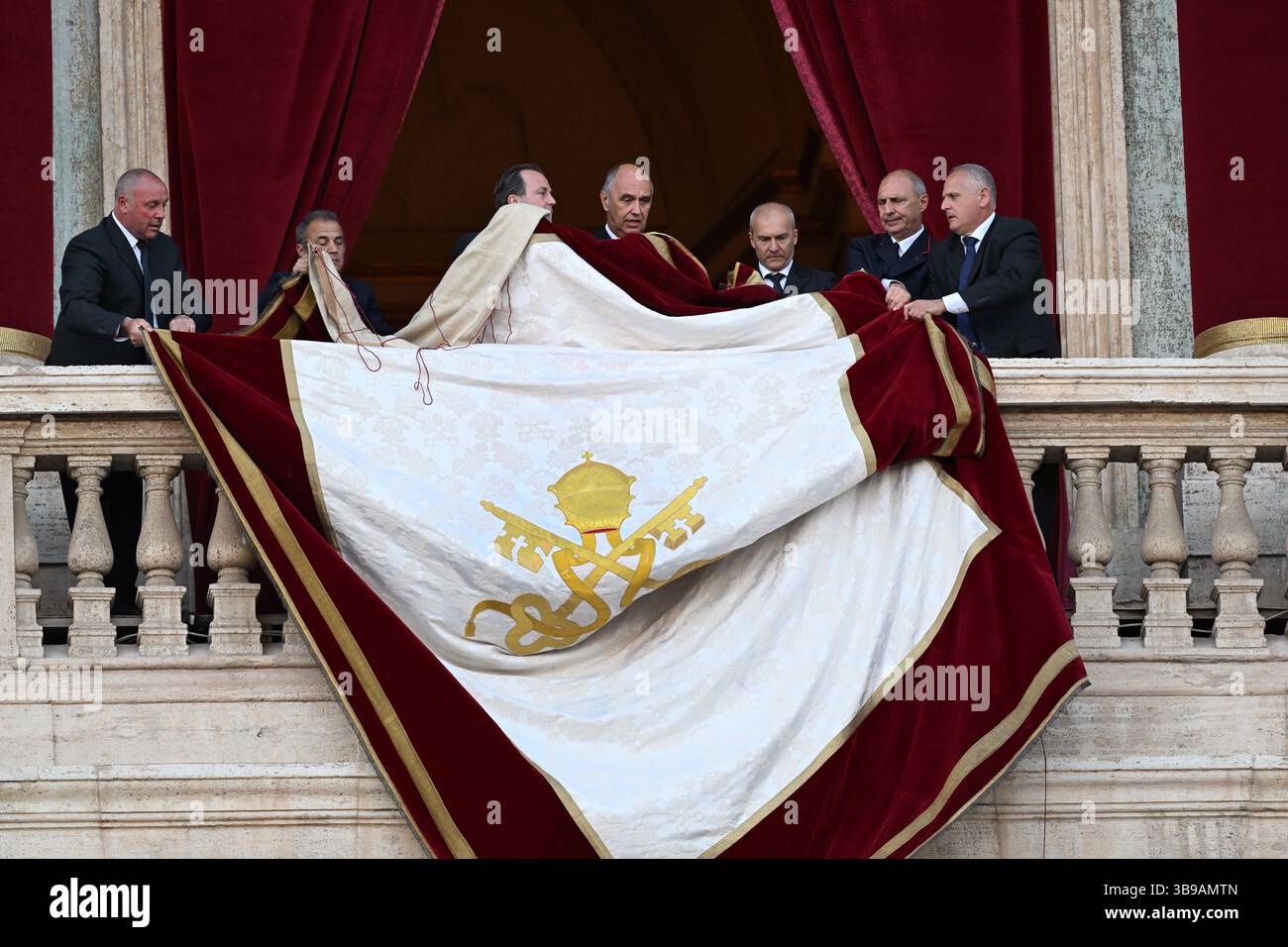 Vatican staff unfurl the papal banner before the newly elected Pope Leo XIV, the American Robert Prevost, steps onto the balcony of St. Peter's Basilica in the Vatican after the conclave on May 8, 2025. Photo by Eric Vandeville/ABACAPRESS.COM Credit: Abaca Press/Alamy Live News Stock Photo