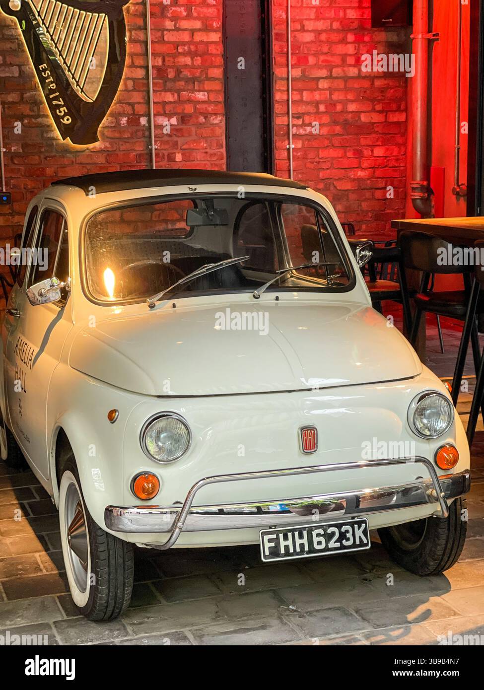 A Fiat 500 in the entrance to a city centre restaurant. Previosly parked on the pavement the icon had attracted a large parking ticket bill, Belfast. - Smartphone Captured Stock Image