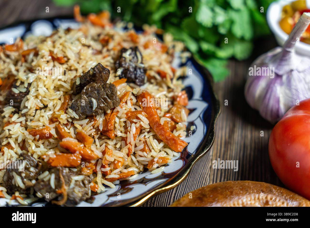 Large dish with Uzbek festive pilaf on wooden background Stock Photo