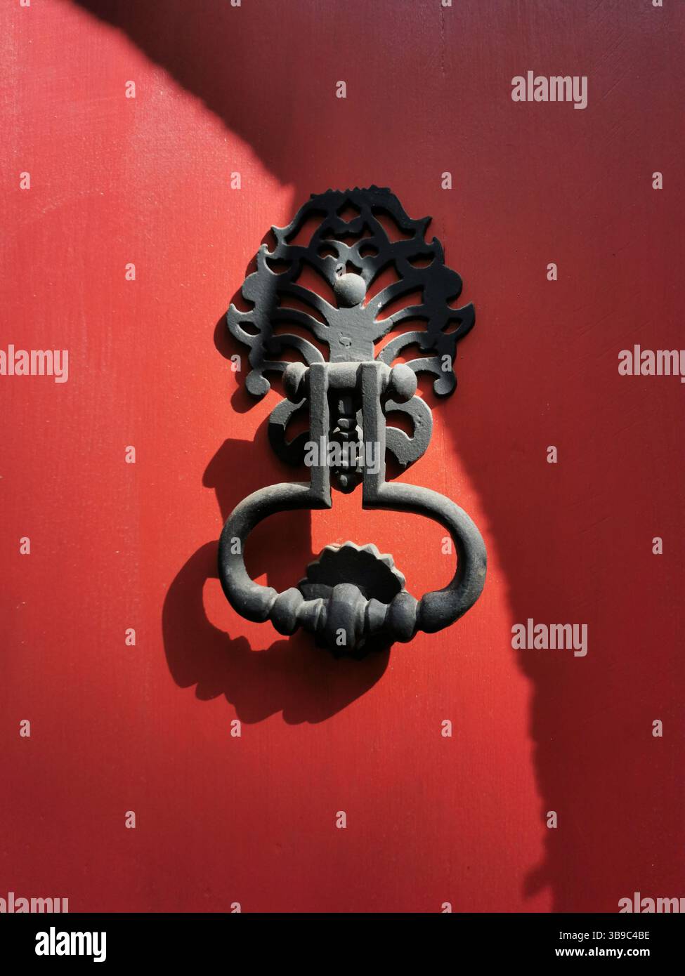 Closeup view of a vintage door knocker on a red door highlighting intricate design and texture Stock Photo