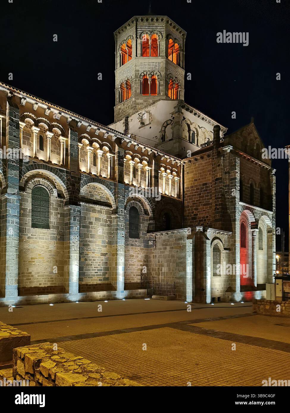 Illuminated Abbatiale Saint Austremoine in Issoire at night, showcasing Puy de Dome in Auvergne Rhone Alpes region of France - Smartphone Captured Stock Image