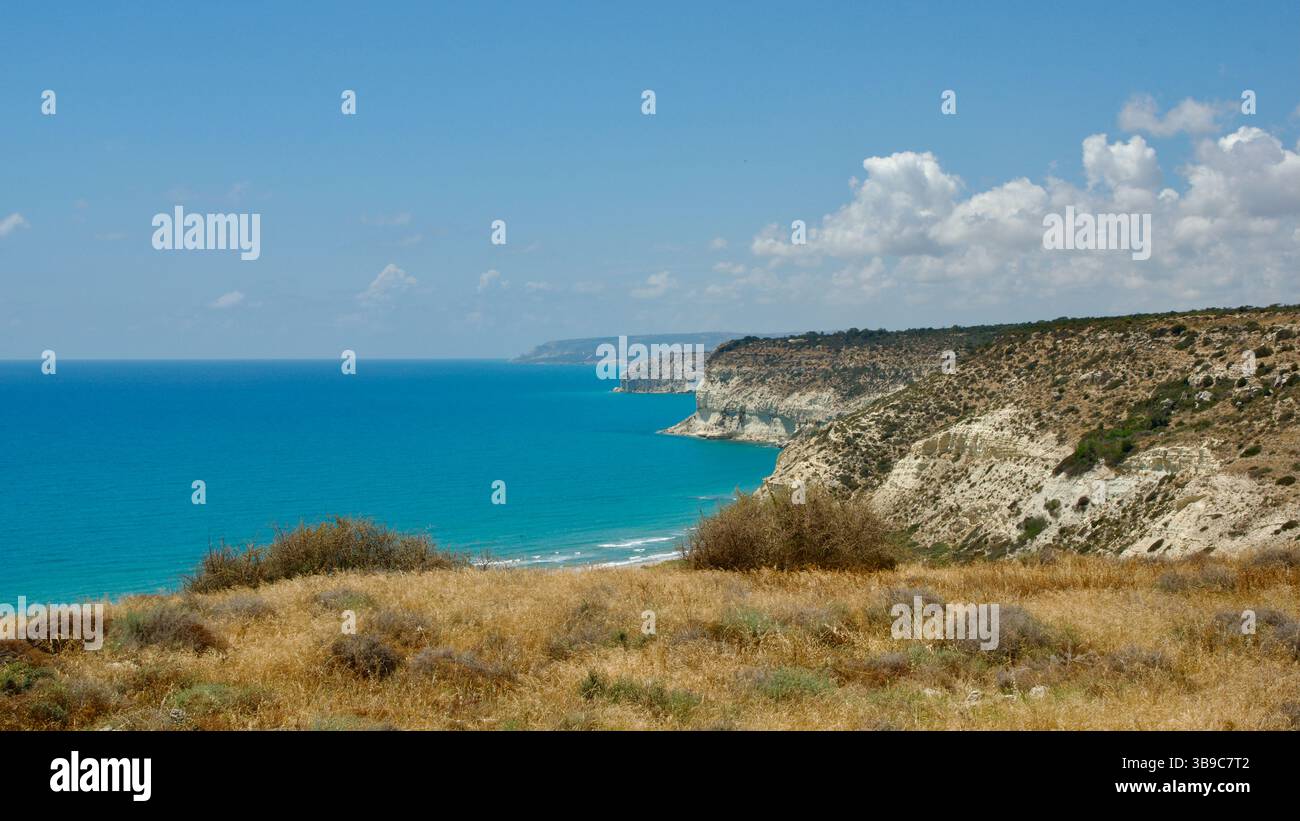 Vivid coastal landscape featuring rugged cliffs and a serene, deep blue ocean under a clear, sunny sky, showcasing the beauty of tranquil nature and p Stock Photo