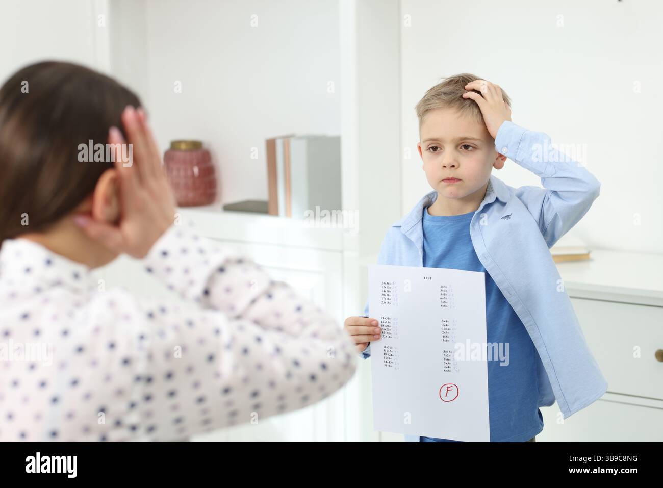 School grade. Sad boy showing answer sheet with bad mark to his mother ...